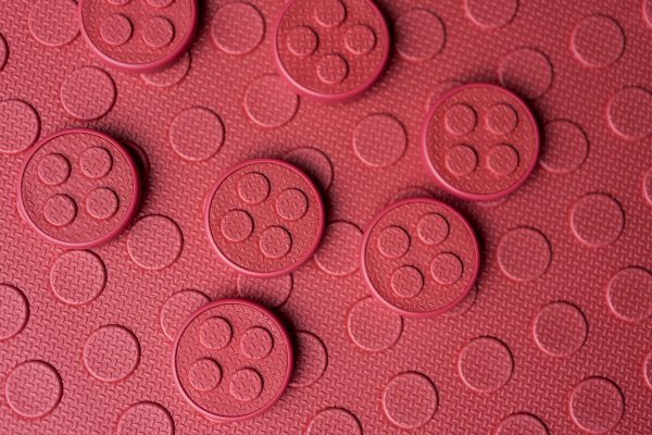 The textured side of the red mat with circular red alphabet tiles scattered on top.