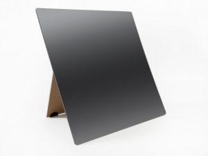 A frameless mirror propped up on its brown stand sitting on a white background.
