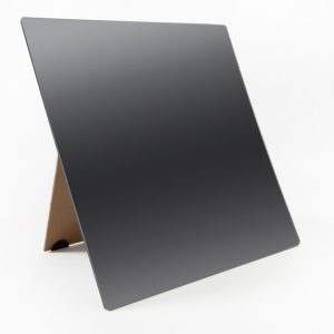 A frameless mirror propped up on its brown stand sitting on a white background.