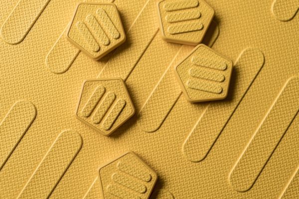 The textured side of the yellow mat with hexagon yellow alphabet tiles scattered on top.