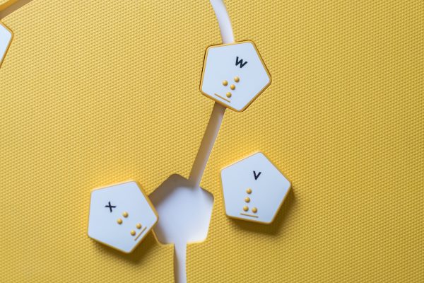 Overhead view of the yellow mat with hexagon cut-outs and a few yellow hexagonal alphabet tiles.