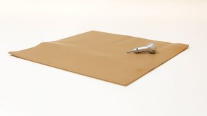 The light brown Swail Dot Inverter pad sitting on a white background with the silver metal stylus sitting on top.