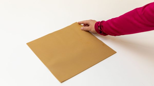 A woman wearing a magenta shirt with her index finger placed on one corner of the brown Swail Dot Inverter Rubber pad.