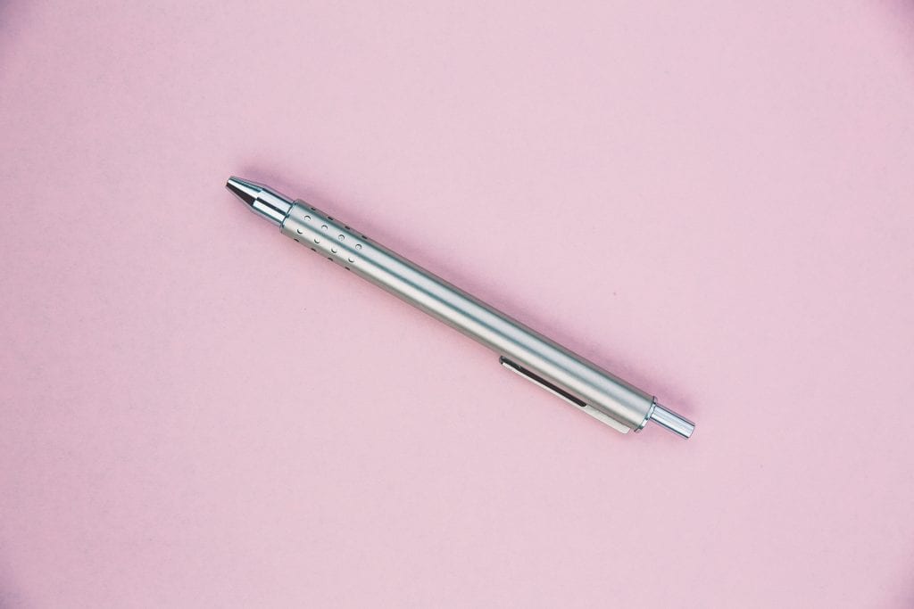 a silver pen on a light pink background