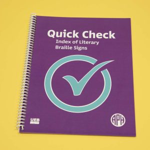 Quick Check Index of Literary Braille Signs Print edition is a spiral-bound book featured over a yellow background. On the purple cover resides a large blue check mark in the middle, a UEB logo in the bottom left-hand corner, and the APH logo in the bottom right-hand corner.