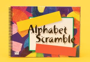 Cover of Alphabet Scramble with UEB icon in the bottom left. The cover contains a variety of colorful graphic shapes that look like crayon drawings beneath a white box containing the title 