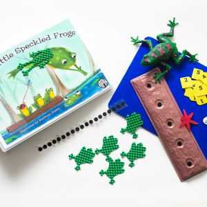 The Five Little Speckled Frogs binder and tactile components laid out on a white background. The kit includes a storyboard, tactile frogs and dragonflies, a log, and combination large print and braille number cards. On the cover of the binder is an illustration of one speckled frog leaping off the hollow log into a pond of blue water. Three frogs remain on the log, and one is catching a dragonfly with its tongue.