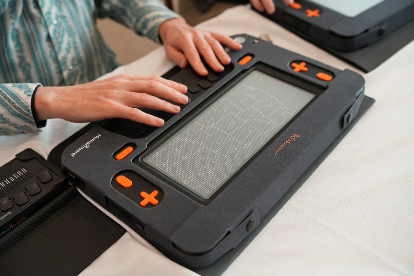 Two hands use the Monarch's Perkins-style keyboard while a tactile graphic depicting a map of the United States is displayed on the Monarch’s multiline refreshable braille display.