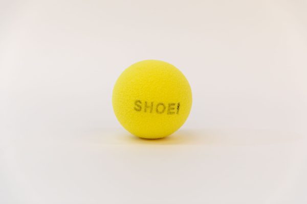 A yellow tennis ball with the word "SHOEI" printed in black