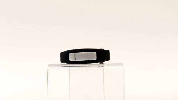 OpticAware device on a clear pedestal against a white background. A silver oval-shaped module fits into a black smart-watch style wearable.