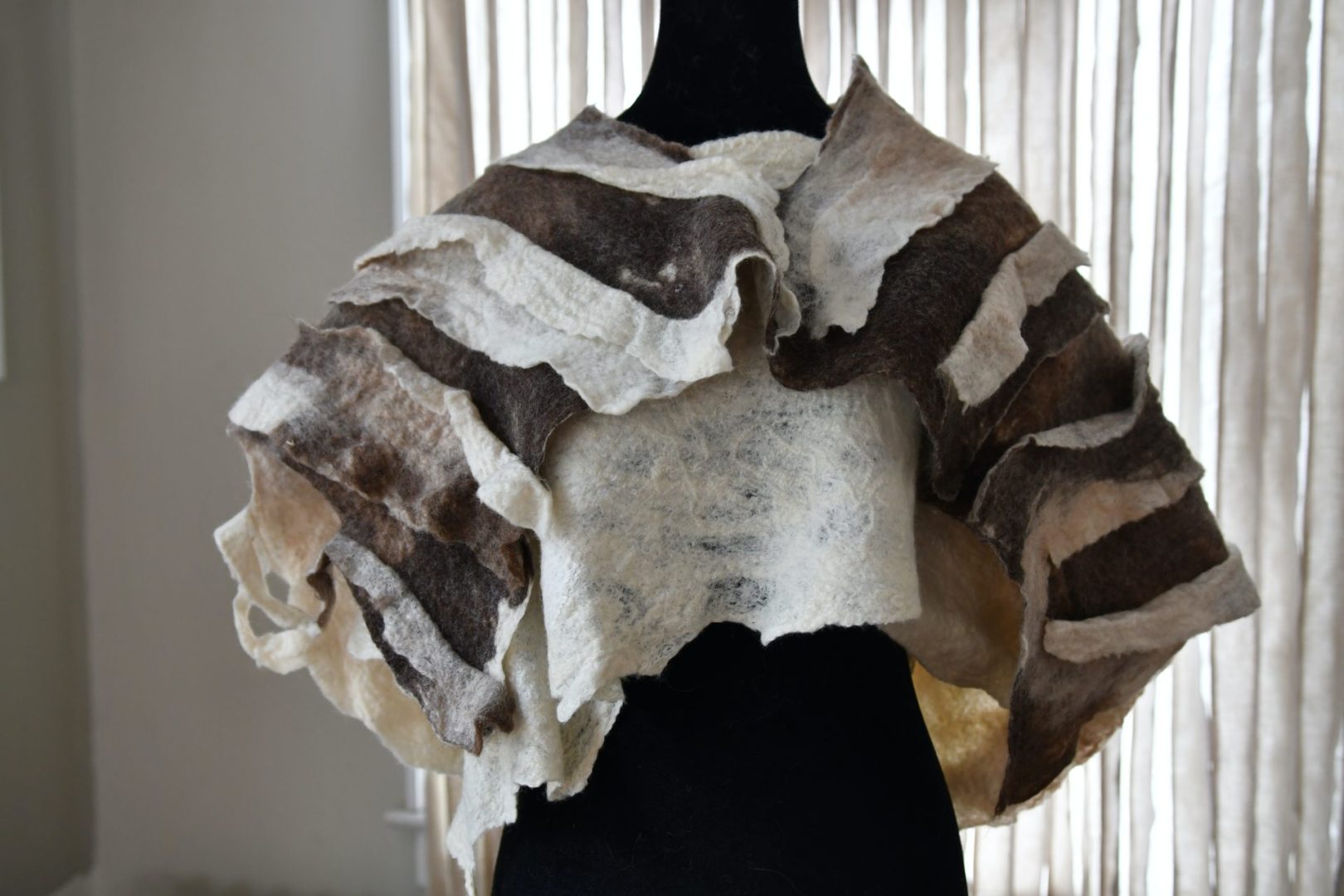 A shawl made from brown and white textured fabric sits on a mannequin.