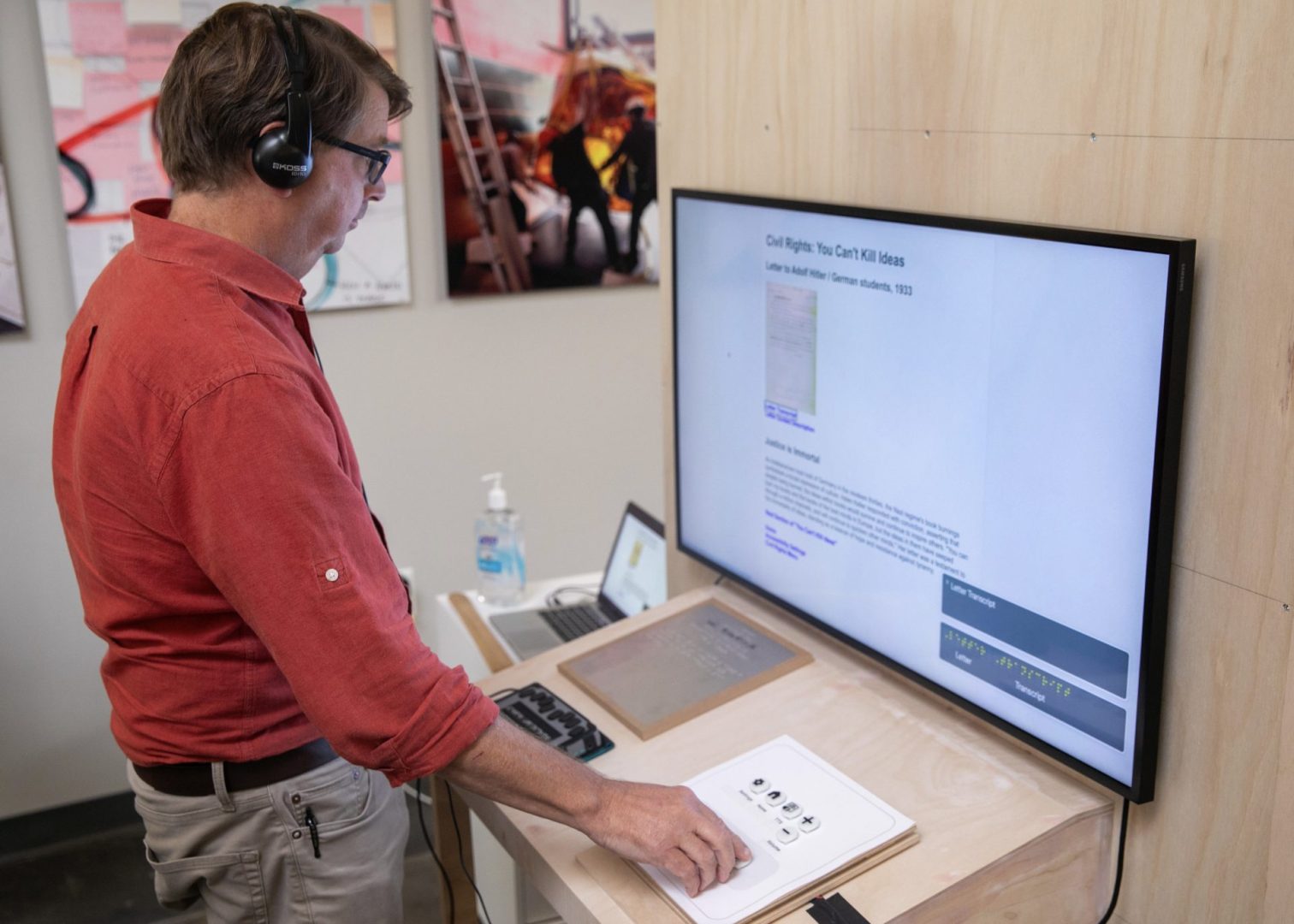 A man stands in front of a TV screen wearing headphones.