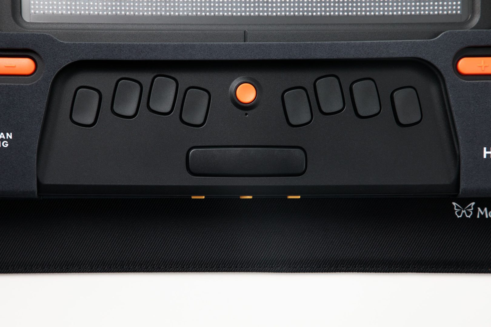 Close up of the Monarch eight-key braille keyboard. There are four keys on each side with a space bar underneath. In the center is an orange circular button called the “action key.” Visible on the edges of the photo are portions of the Monarch, APH, and HumanWare logos.