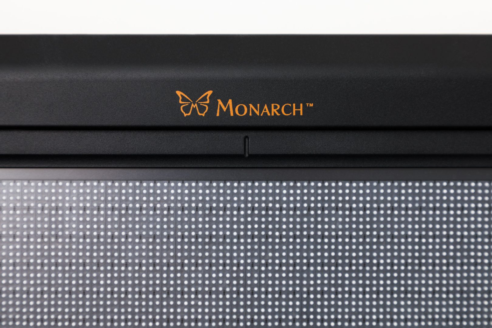 Close up of Monarch logo on the device just above the tactile display. There is a small indentation in the plastic that aligns with the motion sensor.