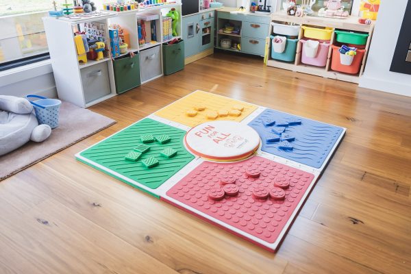 Reach and Match Light assembled on a wooden floor with the textured side up. On each square are tiles of the corresponding color.