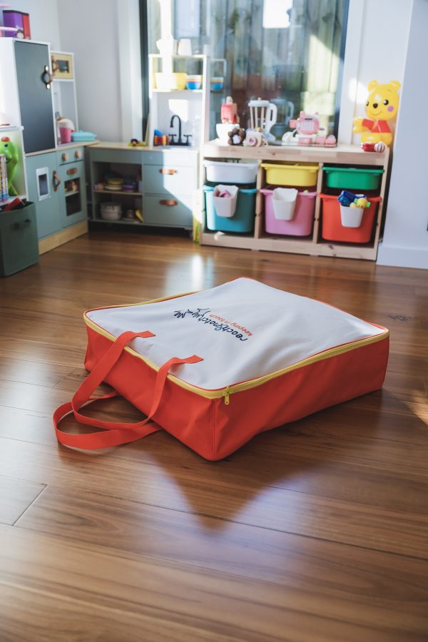 The orange and white Reach and Match Light carrying case on a wooden floor.