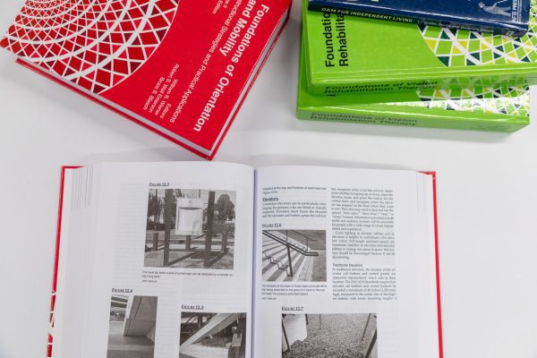 A hardback copy of Volume I opened to a page showing several images of staircases. On the same table, Volume II is positioned above the open book.