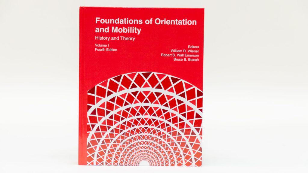 Foundations of Orientation and Mobility, Volume I: History and Theory, 4th edition sitting against a white background. The bottom half of the red cover features a geometric graphic.