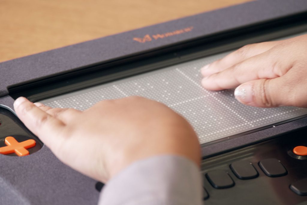 Two hands feel a chart graphic on the Monarch's refreshable braille display.