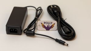 Power adapter and power cord on a white background with a Polly keychain sitting in between.