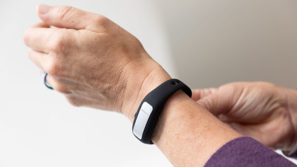 Two hands of a woman adjusting the closure on an OpticAware band on her wrist.