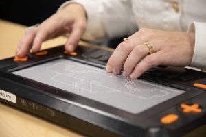 Two hands explore a car tactile graphic on the Monarch.