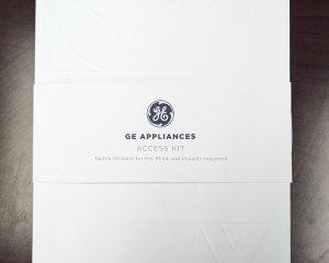 A white folder with the GE appliances logo against a dark wood background.