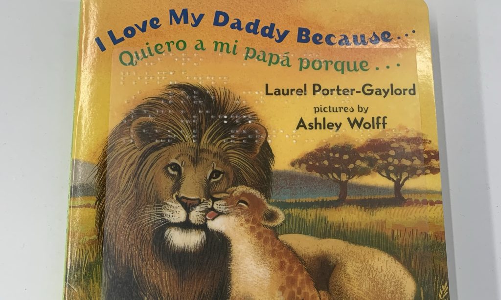 A book featuring a brown lion, with a small cub on its right kissing the lions nose appears under the phrase 